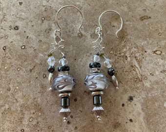 May include: A pair of silver dangle earrings with black and white glass beads, silver beads, and clear crystal beads.