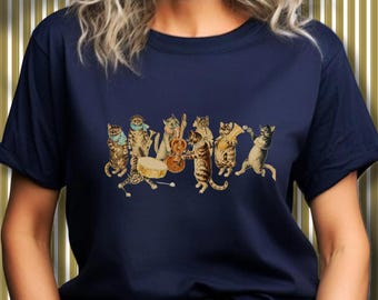 May include: Navy blue t-shirt featuring a whimsical illustration of a cat band. The band consists of several cats playing various instruments, including a guitar, drums, and a trombone. The cats are depicted in a vintage style, adding a touch of retro charm.