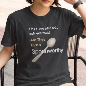 May include: Dark gray t-shirt with the text "This weekend, ask yourself Are They Even Spoonworthy" and a graphic of a spoon. The text is in white and gold, with the word "Are" in gold. The spoon graphic is silver.