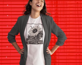 Könnte beinhalten: Ein weißes T-Shirt mit einer schwarz-weißen Sonnenblumenillustration. Die Person trägt einen dunkelgrauen Blazer. Der Hintergrund ist eine leuchtend rote Wellblechoberfläche.