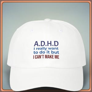 Può includere: Cappellino da baseball bianco con la scritta "A.D.H.D I really want to do it but I CAN'T MAKE ME" in blu e bordeaux. Il cappellino ha una visiera curva e un bottone sulla parte superiore.