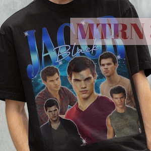 Może przedstawiać: Czarny t-shirt z grafiką przedstawiającą grupę mężczyzn oraz niebieskim napisem "JAC Black". Model ma na sobie czarny kapelusz rybacki. Koszulka to regularny krój, unisex.