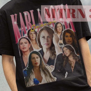 May include: Black t-shirt with a collage of images of women, including the text "KARLA MORAN" and "Gaccon". The model is wearing a black bucket hat.