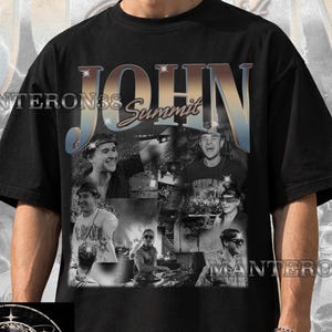 May include: A black short-sleeve t-shirt featuring a collage of black and white photographs of a person performing as a DJ. The text JOHN SUMMIT is printed in large, metallic-toned letters at the top, with additional small star graphics.