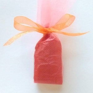 May include: A small, red gift bag wrapped in pink tulle and tied with an orange ribbon.