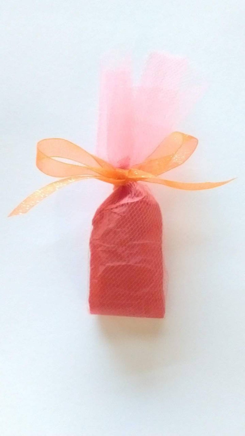May include: A small, red gift bag wrapped in pink tulle and tied with an orange ribbon.
