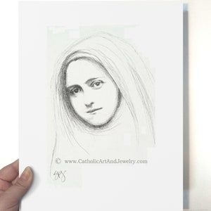 May include: A black and white pencil drawing of a young woman with long hair, wearing a veil. The drawing is signed "SYG" and includes the website "www.CatholicArtAndJewelry.com".