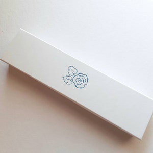 May include: A white rectangular box with a blue rose design printed on the top.