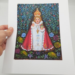 May include: A painting of a young child wearing a red and white robe, a crown, and holding a cross. The child is surrounded by flowers and greenery.