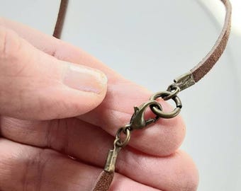May include: A brown leather cord necklace with a bronze lobster clasp.