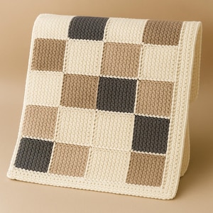 Könnte beinhalten: Eine gehäkelte Decke mit einem karierten Muster in Beige, Braun und Grau.