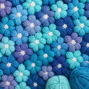 Puede incluir: Primer plano de una manta de ganchillo hecha de flores azules y moradas. Dos ovillos de lana están en primer plano.