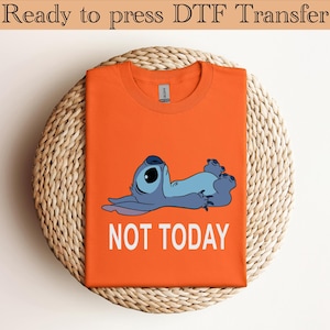 K&ouml;nnte beinhalten: Ein leuchtend orangefarbenes T-Shirt mit Rundhalsausschnitt und einer Grafik eines blauen Alien-Charakters, der auf dem R&uuml;cken liegt, mit dem darunter gedruckten wei&szlig;en Text NOT TODAY. Das Shirt hat ein klassisches Kurzarmdesign und ein Etikett.