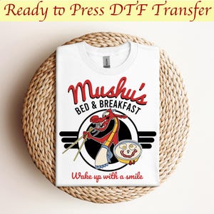 May include: White t-shirt with a black and white circle graphic featuring a red dragon holding chopsticks and a bowl of eggs with a smiley face. The text "Mushu's Bed & Breakfast" is above the graphic and "Wake up with a smile" is below the graphic.