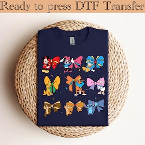 May include: A navy blue t-shirt with a design of various Disney characters wearing colorful bows. The characters include Mickey Mouse, Minnie Mouse, Donald Duck, Goofy, Pluto, and Stitch.