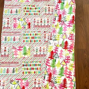 May include: A Christmas-themed quilt with a white background. The quilt features various rectangular patterns with images of Christmas trees, nutcrackers, and diamond shapes. The color palette includes red, green, pink, and white.