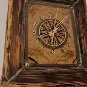 May include: A rustic wooden clock with a rope border and a natural wood face. The clock hands are gold and the numbers are black. The clock is set against a white wall.