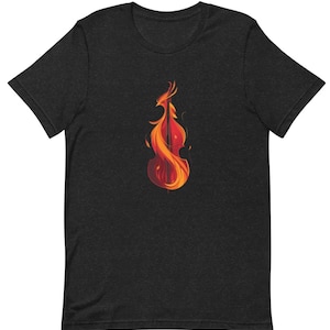 以下が含まれることがあります： 炎に包まれたチェロのグラフィックがプリントされた黒いTシャツ。チェロは黒で縁取られ、炎はオレンジと黄色です。