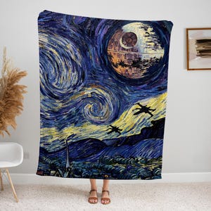 May include: A large, rectangular blanket featuring a stylized painting of a space scene. The design incorporates elements of Van Gogh's "Starry Night" with a Death Star and X-wing fighters. The color palette includes blues, yellows, and dark hues.