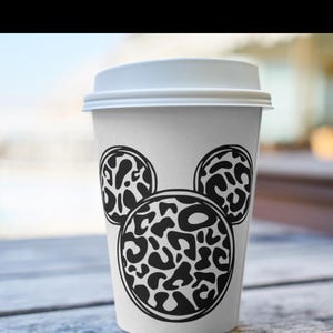 Peut inclure: Un gobelet &agrave; caf&eacute; blanc &agrave; emporter avec un motif Mickey Mouse en imprim&eacute; l&eacute;opard noir et blanc.