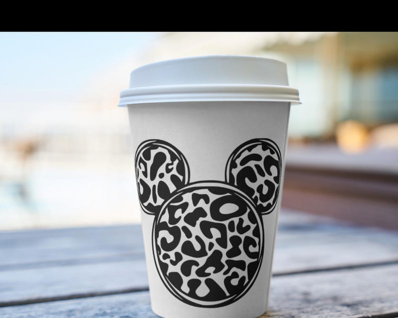 Peut inclure: Un gobelet &agrave; caf&eacute; blanc &agrave; emporter avec un motif Mickey Mouse en imprim&eacute; l&eacute;opard noir et blanc.
