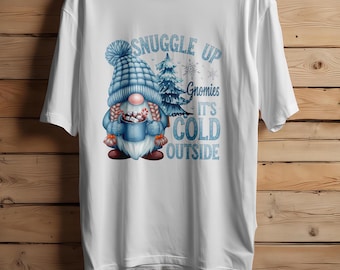 May include: White t-shirt with a blue gnome holding a mug of hot chocolate. The text "Snuggle Up Gnomes It's Cold Outside" is printed on the shirt.