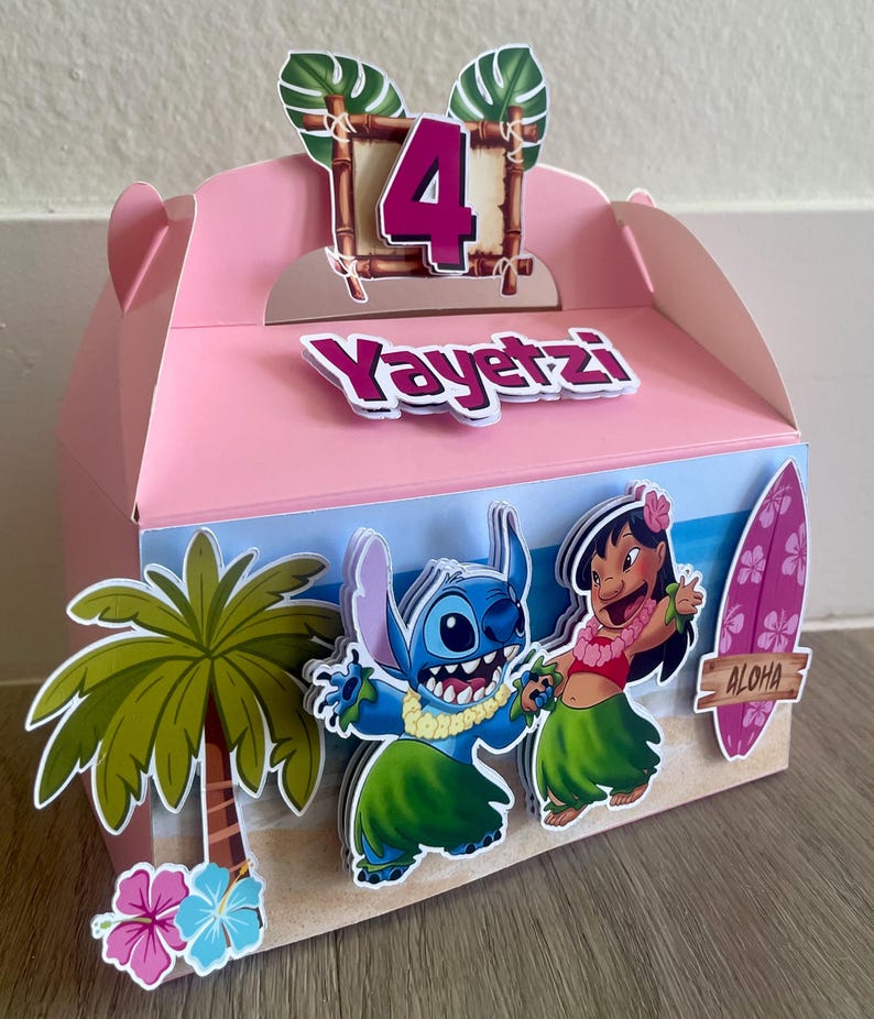 May include: Pink party favor box decorated with a tropical theme. Features the number 4, the name "Yayetzl", and cartoon characters Stitch and Lilo. Includes a palm tree, flowers, and a surfboard with the word "Aloha".