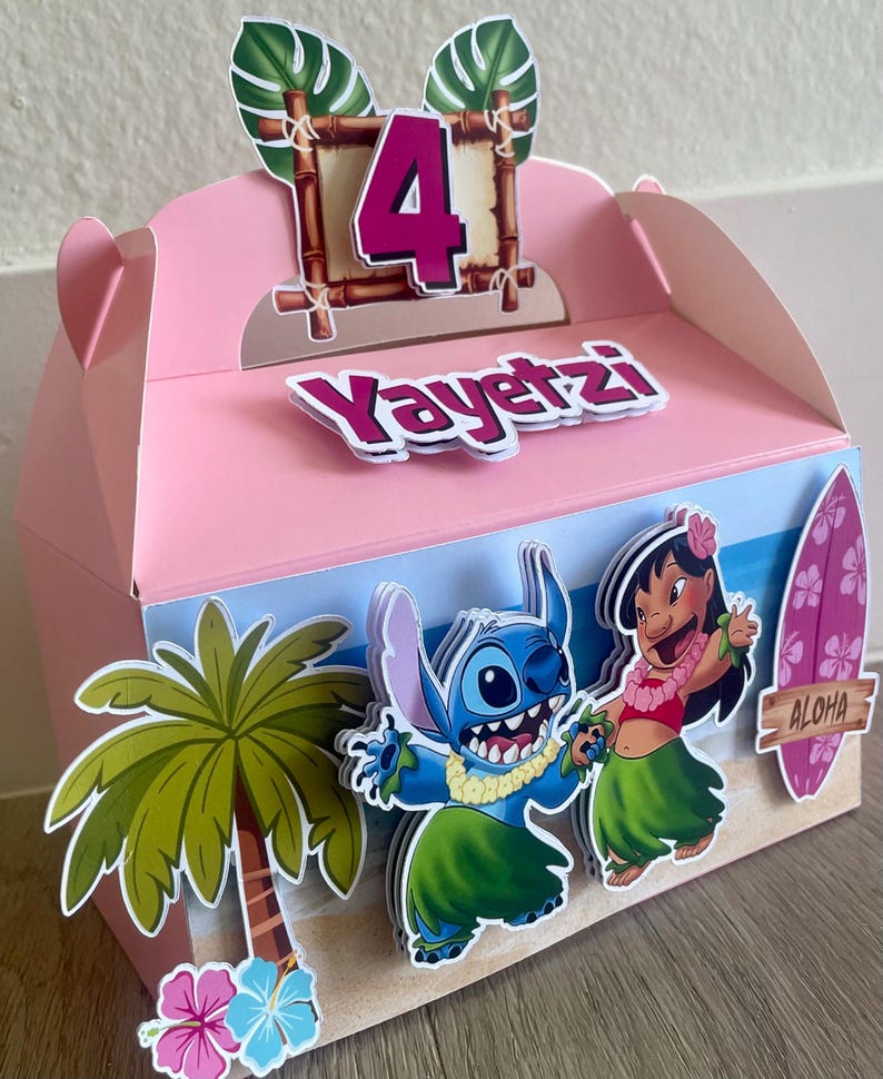 May include: Pink party favor box decorated with a tropical theme. Features the number 4, the name "Yayetz", and cartoon characters Stitch and Lilo. Includes a palm tree, flowers, and a surfboard with "Aloha" text.