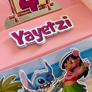 May include: Pink party favor box with the name "Yayetzl" in white letters with a pink outline. The box features a number 4 in pink, a cartoon of Stitch and Lilo, and a tropical beach scene.