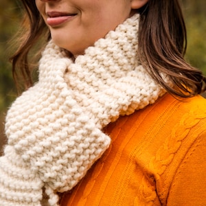 A close up shot of a woman wearing the finished cream colored scarf.