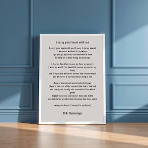 May include: A framed print with the poem "i carry your heart with me" by E.E. Cummings. The poem is in black text on a light gray background, with a white border. The frame is white.