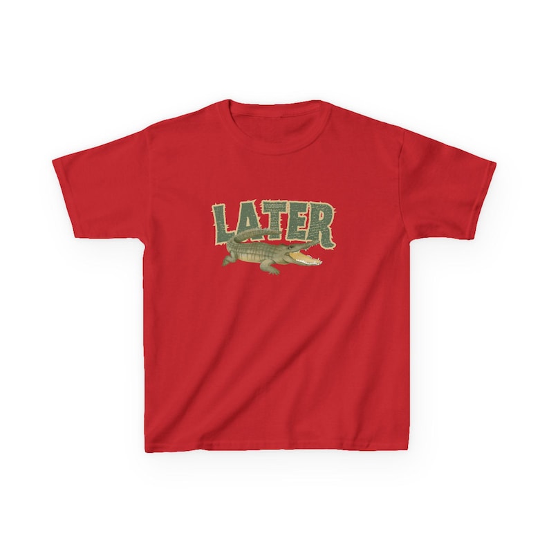 May include: Red t-shirt featuring the word "LATER" in a green, textured font above a cartoon alligator. The alligator is green and tan with an open mouth. The shirt is a short-sleeved crew neck.