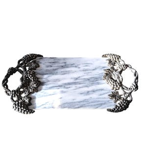 May include: A rectangular white marble serving tray featuring gray veining and two metallic handles. Each handle is shaped like a grapevine with detailed leaves and clusters of grapes, providing a decorative grip on both sides.