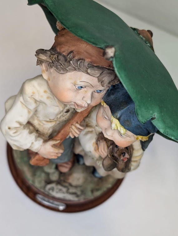 A. ベルカリ作カポディモンテの置物 – 緑の傘の下の男の子と