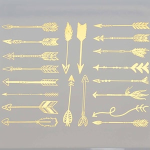 May include: A white ceramic tile with a gold design of various arrows. The arrows are in different styles and sizes, and some have feathers.