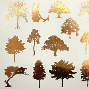 May include: A sheet of gold foil stickers featuring various tree silhouettes. The trees are in different styles and sizes, with some having bare branches and others having full foliage.