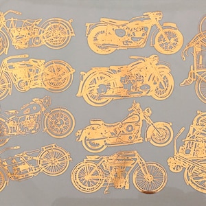 Peut inclure: Une collection de dix silhouettes de motos dorées sur un fond gris. Les motos sont de styles et de tailles différents, et certaines ont des side-cars.