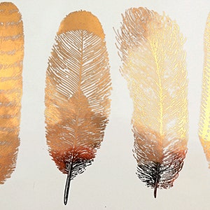 May include: Four gold metallic feather tattoos. The feathers are detailed and have a realistic look.