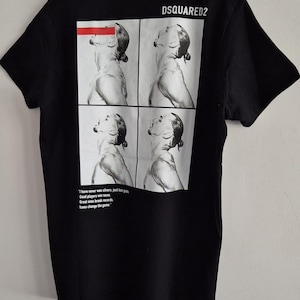 May include: Black t-shirt featuring a four-panel image of a person with their head tilted back. The shirt has the text "DSQUARED2" at the top and a quote at the bottom: "I have never won silvers, just lost gold. Good players win races. Great ones break records. Icons change the game."