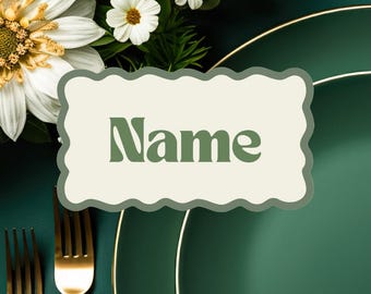 Könnte beinhalten: Eine grüne Platzkarte mit weißem Rand und dem Wort "Name" in grüner Schrift. Die Platzkarte liegt auf einem grünen Teller mit goldenem Rand.