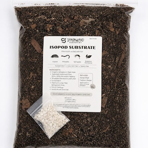 May include: A clear plastic bag filled with dark brown isopod substrate, featuring a white label with the text Shadowland Serpentry Isopod Substrate. The bag includes a small, separate clear pouch containing white oyster shell calcium pieces.
