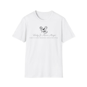 Puede incluir: Camiseta blanca con cuello redondo y estampado de pájaro. El diseño incluye un pájaro con las alas extendidas sobre el texto "Lady J Micro Magic" y la frase "Farm-to-Table Freshness, Miniature Style" en negro.