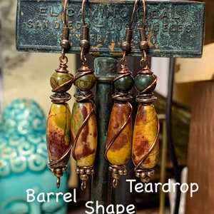 May include: Three pairs of earrings with copper wire wrapped around teardrop and barrel shaped stones. The stones are a mix of brown, yellow, and green.