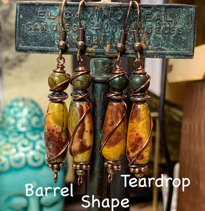 May include: Three pairs of earrings with copper wire wrapped around teardrop and barrel shaped stones. The stones are a mix of brown, yellow, and green.