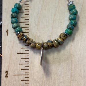 May include: A silver hoop earring with a turquoise and brown bead design. The earring is approximately 1 inch in diameter.