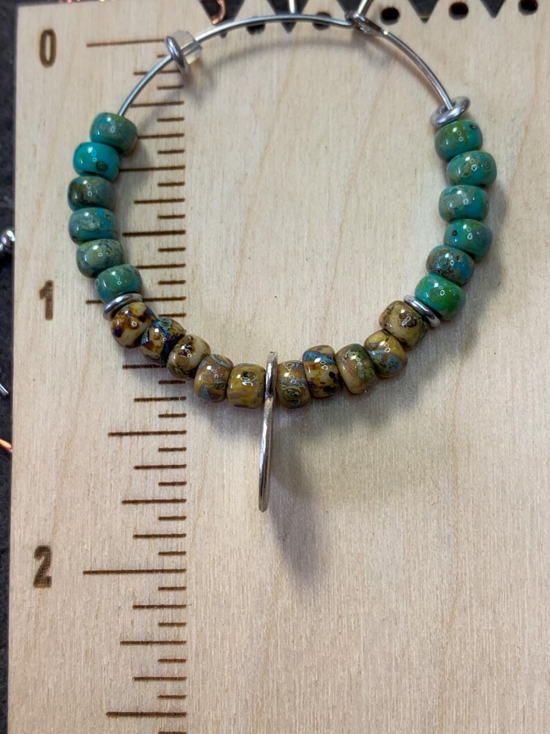 May include: A silver hoop earring with a turquoise and brown bead design. The earring is approximately 1 inch in diameter.