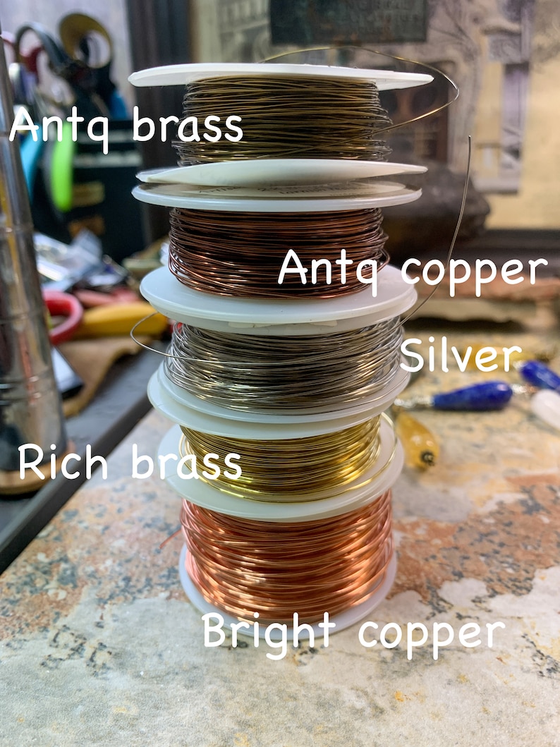 May include: A stack of spools of wire in different colors and finishes, including antique brass, antique copper, silver, rich brass, and bright copper.