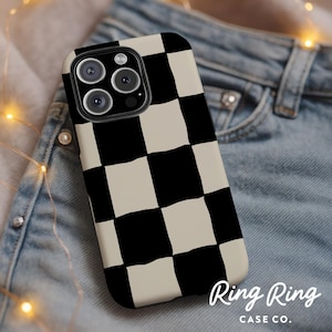 May include: A phone case with a black and cream checkerboard pattern. The case has a glossy finish and covers the back and sides of the phone. The Ring Ring Case Co. logo is visible in the bottom right corner. The phone case is resting on a pair of blue jeans.