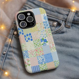 May include: A floral patchwork phone case featuring a variety of pastel colors, including pink, blue, and green. The case has a glossy finish and a camera cutout. The design is reminiscent of a quilt.