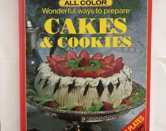 May include: A red cookbook with the title "ALL COLOR Wonderful ways to prepare CAKES & COOKIES" and a picture of a cake decorated with fruit and chocolate on the cover. The book also says "FULL COLOR PLATES over 170 NEW recipes".